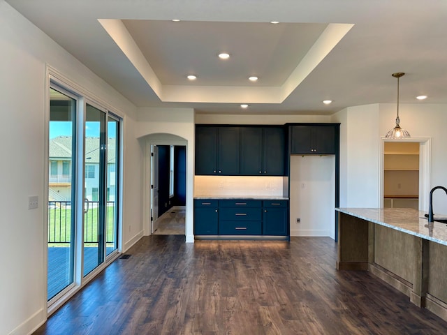 kitchen featuring light stone counters, recessed lighting, a raised ceiling, and dark wood-type flooring