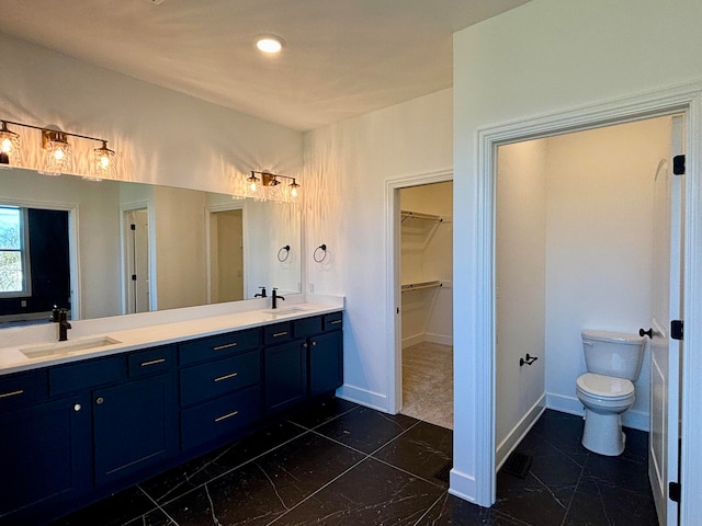 bathroom with baseboards, a sink, toilet, and double vanity