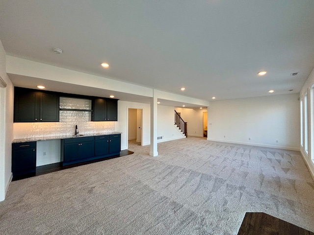 unfurnished living room featuring baseboards, stairway, light colored carpet, and recessed lighting