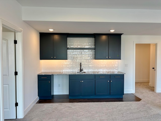 kitchen with light countertops, a sink, backsplash, and blue cabinetry