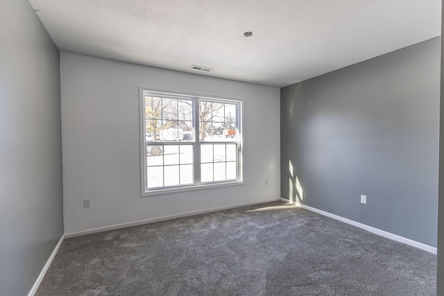 unfurnished room with a textured ceiling and dark carpet