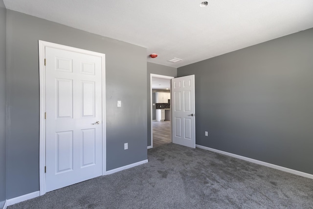 unfurnished bedroom with dark colored carpet