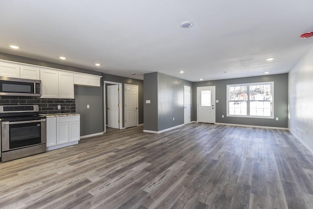 kitchen with stainless steel appliances, dark wood-type flooring, white cabinets, and decorative backsplash