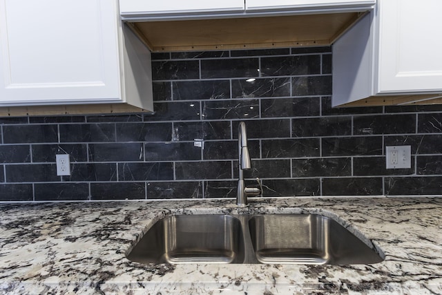 kitchen featuring sink, white cabinetry, stone countertops, and decorative backsplash