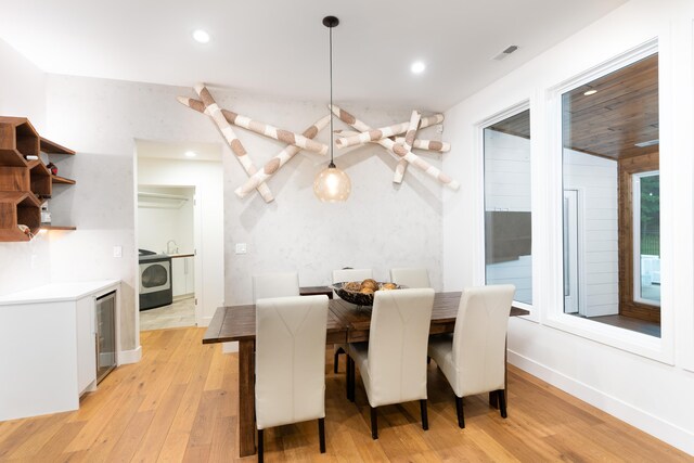 dining room featuring sink, light hardwood / wood-style flooring, washer / dryer, and wine cooler