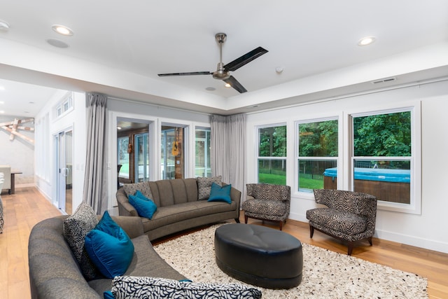 living room featuring plenty of natural light, light wood-type flooring, and ceiling fan