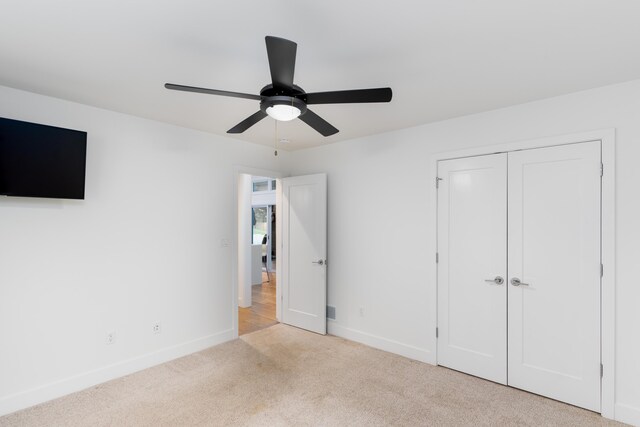 unfurnished bedroom featuring light carpet, a closet, and ceiling fan