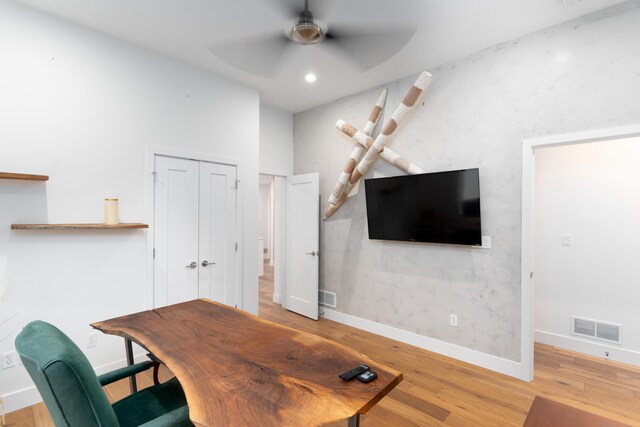 home office with light hardwood / wood-style flooring and ceiling fan