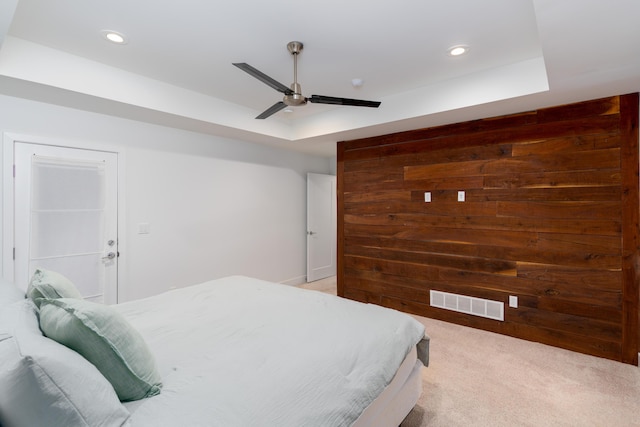 carpeted bedroom featuring ceiling fan and a tray ceiling