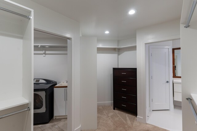 walk in closet featuring washer / clothes dryer and light carpet