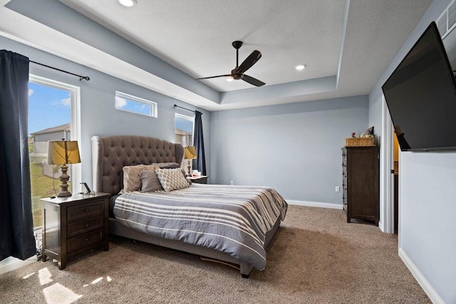 bedroom featuring carpet flooring, a textured ceiling, a raised ceiling, and ceiling fan