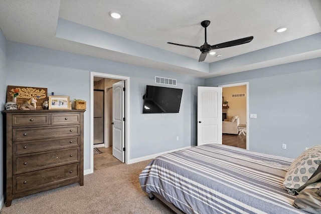 carpeted bedroom featuring ceiling fan and a raised ceiling