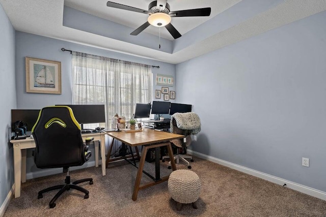 carpeted office featuring ceiling fan and a raised ceiling