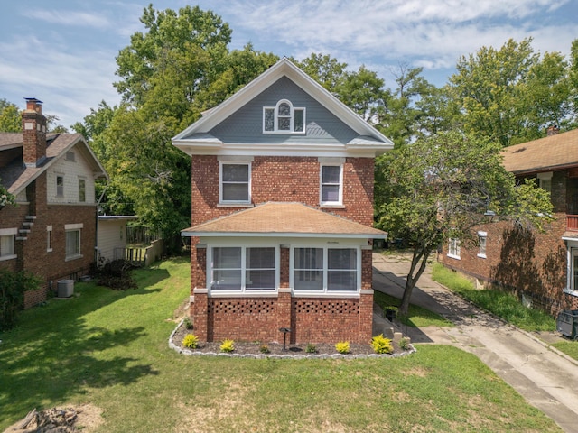 traditional style home featuring a front yard, brick siding, and cooling unit