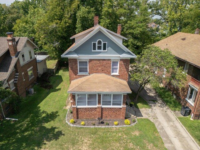 view of front of property featuring a front yard, a chimney, and brick siding