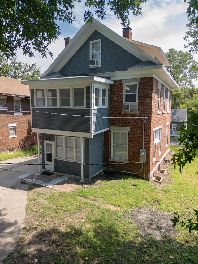 exterior space with a chimney, a front lawn, cooling unit, and brick siding