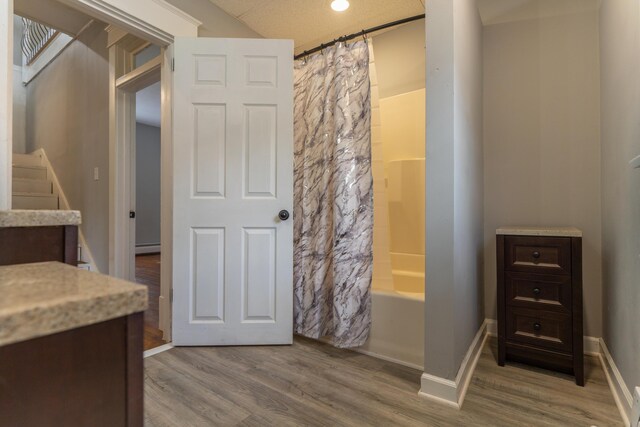 bathroom featuring baseboards, shower / bath combo with shower curtain, wood finished floors, and vanity