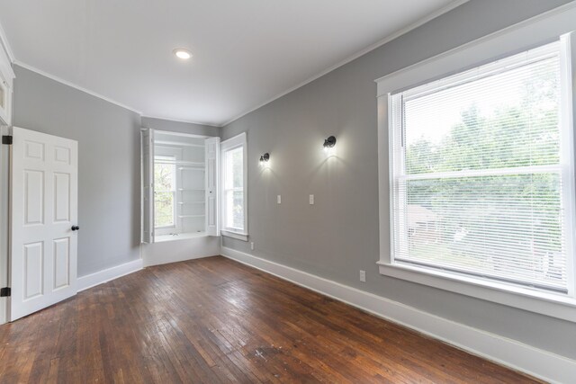 unfurnished room with dark wood-style floors, baseboards, and ornamental molding