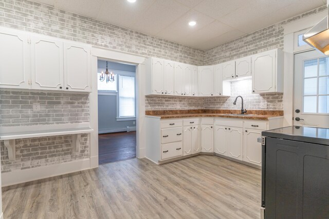 kitchen with light wood-style flooring, a baseboard heating unit, a sink, white cabinetry, and black electric range