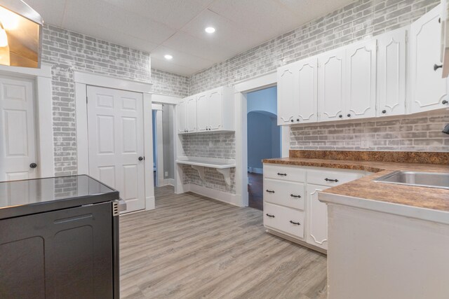 kitchen with tasteful backsplash, recessed lighting, light wood-style flooring, white cabinetry, and a sink