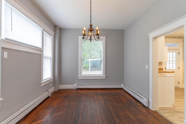 unfurnished dining area featuring a baseboard radiator, wood finished floors, and a notable chandelier