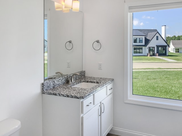 bathroom with vanity, toilet, and a healthy amount of sunlight