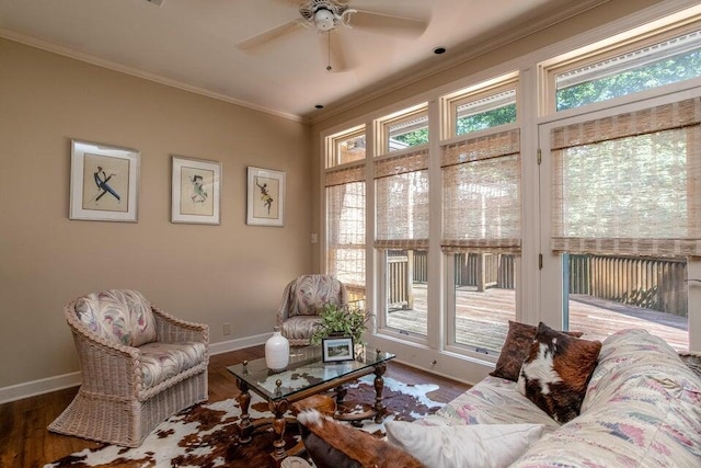 living area featuring ceiling fan, baseboards, crown molding, and wood finished floors