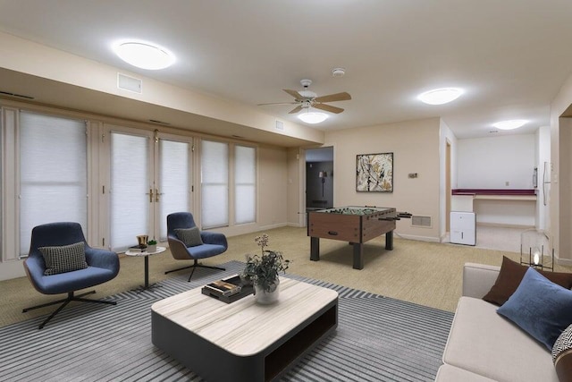 living area featuring light carpet, baseboards, visible vents, and ceiling fan