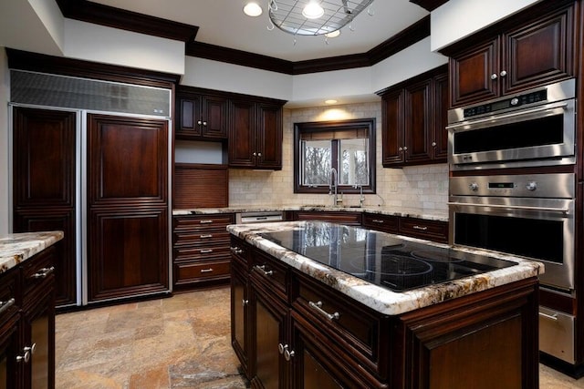 kitchen featuring paneled fridge, stainless steel double oven, black electric cooktop, a sink, and ornamental molding