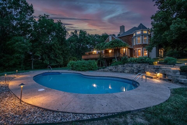 pool at dusk featuring a deck, a patio, and an outdoor pool