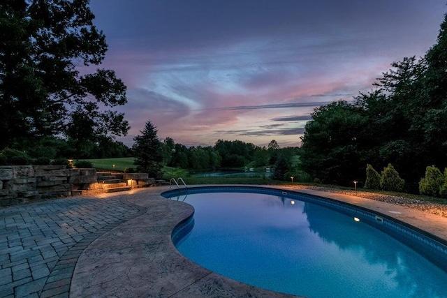 pool at dusk featuring a patio area and an outdoor pool