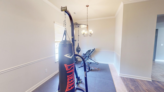 exercise room with a notable chandelier, wood-type flooring, and ornamental molding