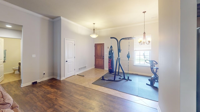 exercise room with hardwood / wood-style floors, an inviting chandelier, and ornamental molding