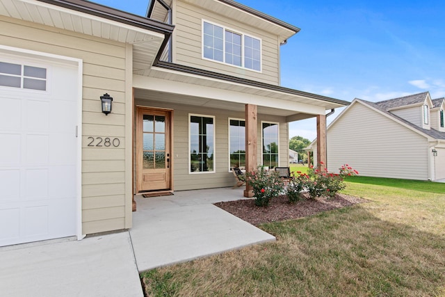 property entrance with a lawn, a garage, and covered porch