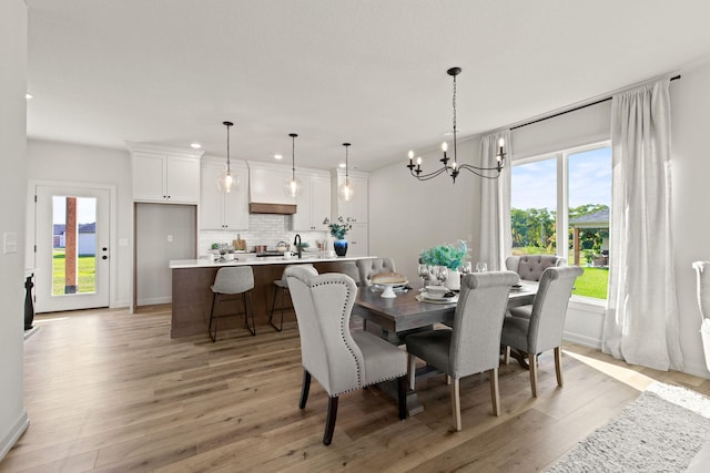 dining room with light wood-type flooring, a notable chandelier, and plenty of natural light