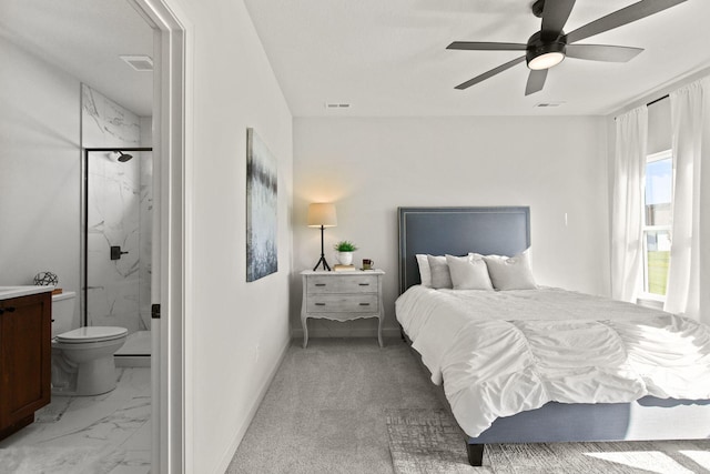 carpeted bedroom with ensuite bath and ceiling fan