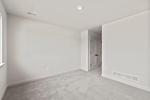 carpeted spare room with a textured ceiling