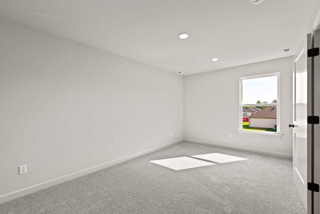 spare room featuring light colored carpet and a textured ceiling