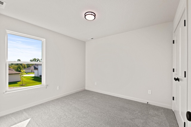 carpeted empty room featuring a textured ceiling