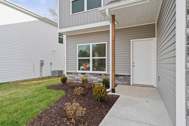 view of exterior entry with cooling unit and a lawn