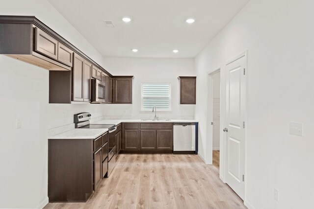 kitchen with dark brown cabinets, sink, light wood-type flooring, and stainless steel appliances