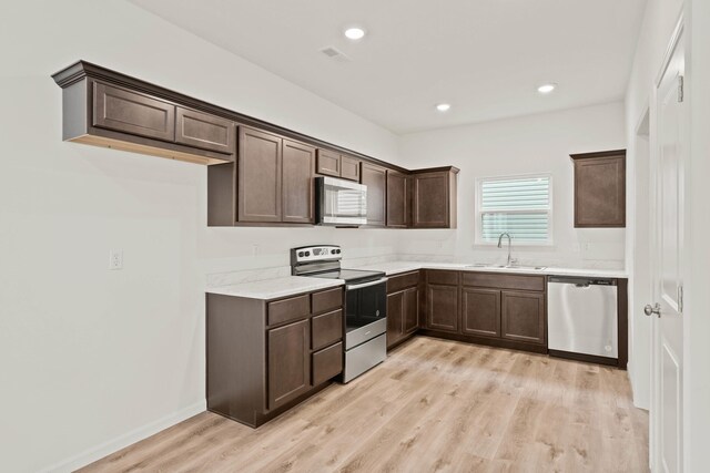 kitchen featuring sink, stainless steel appliances, dark brown cabinets, and light hardwood / wood-style floors