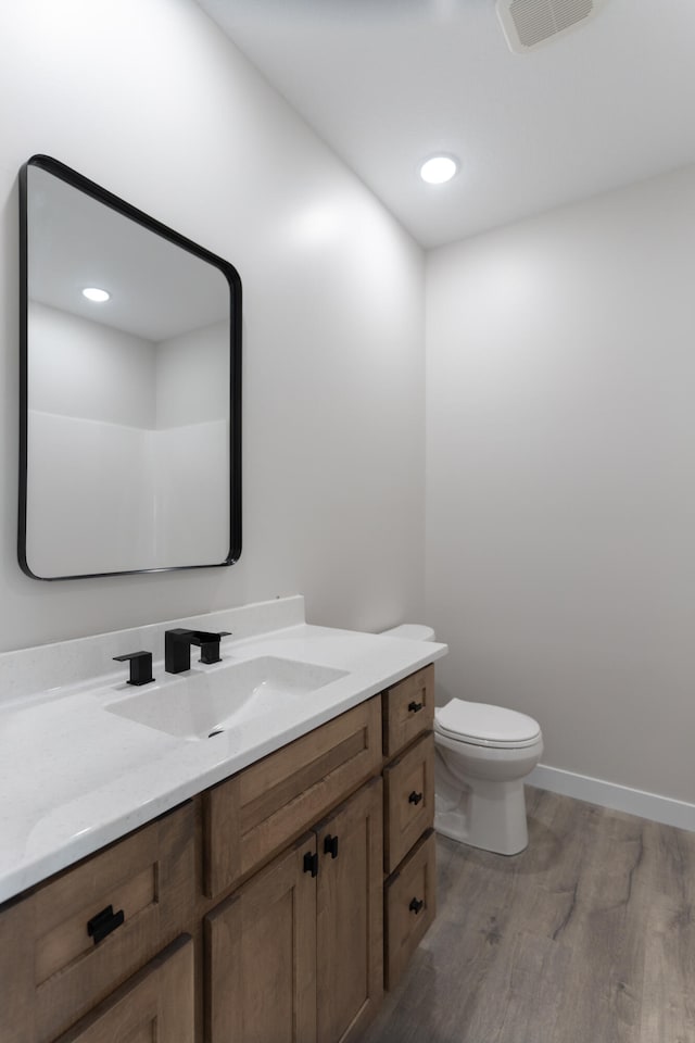 bathroom with toilet, hardwood / wood-style flooring, and vanity