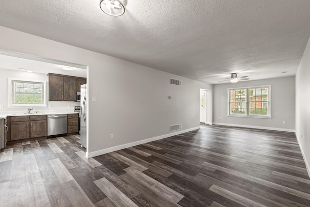 unfurnished living room featuring sink, a wealth of natural light, and dark wood-type flooring