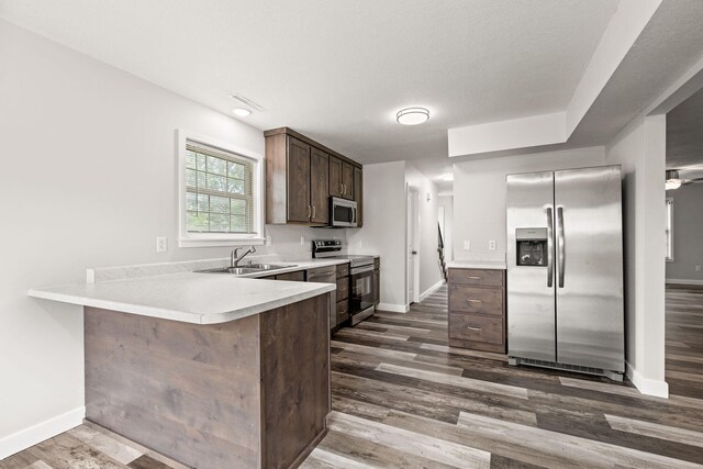 kitchen featuring appliances with stainless steel finishes, sink, wood-type flooring, and dark brown cabinetry