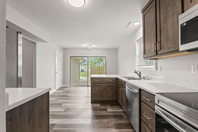 kitchen with sink, stainless steel appliances, dark hardwood / wood-style floors, and a textured ceiling