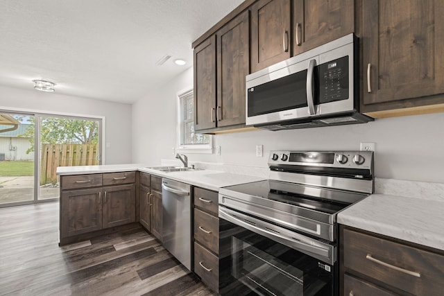 kitchen featuring dark brown cabinetry, sink, dark wood-type flooring, and appliances with stainless steel finishes