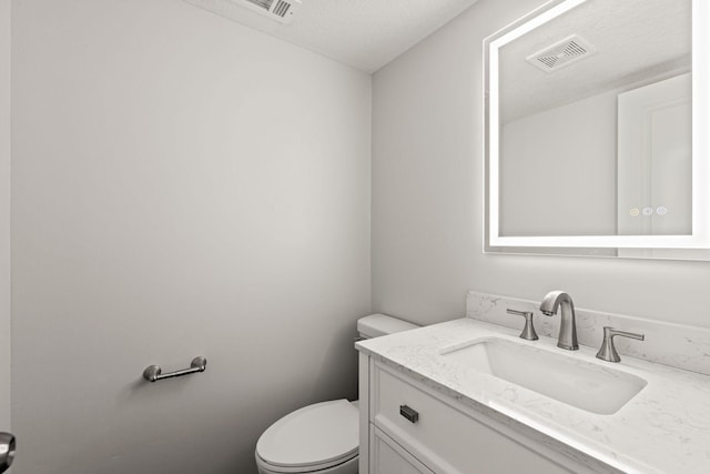 bathroom featuring vanity, toilet, and a textured ceiling