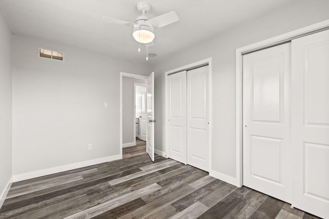 unfurnished bedroom with multiple closets, dark wood-type flooring, and ceiling fan