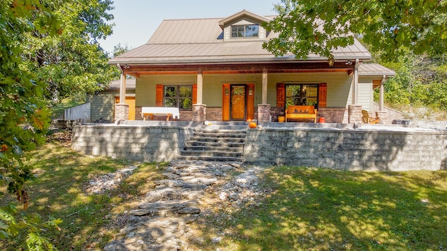 view of front of home featuring covered porch, stone siding, and metal roof